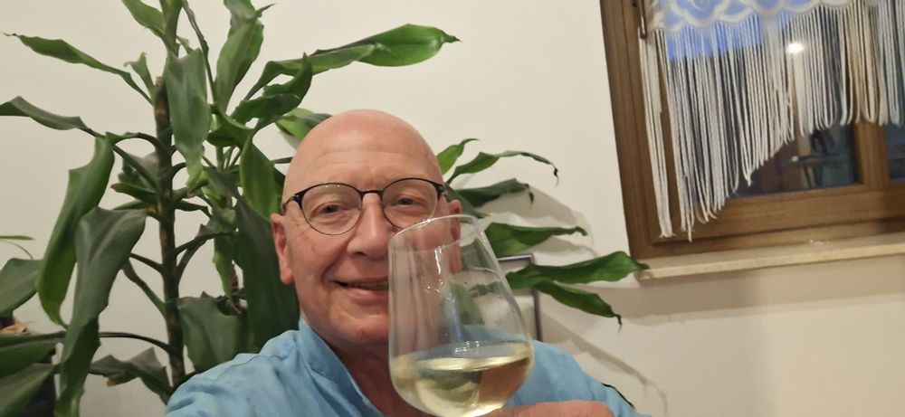 Mann vor Blume mit Weinglas in der Hand