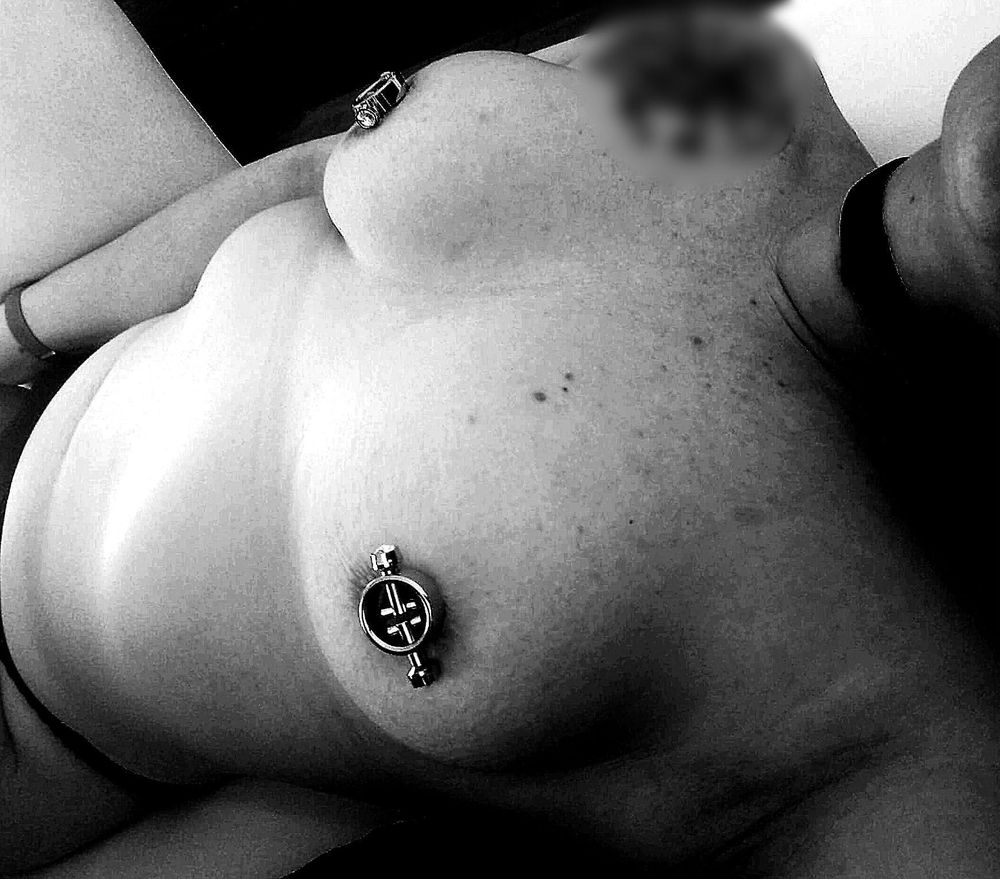 Schwarz-weiß Foto. Am rechten Rand mein Kinn und Hals mit Halsband, dann meine Brüste mit Magnet-Nippelklemmen, mein Bauch und links mein Höschen. Meine Hand hält etwas, das auf dem Höschen über meiner Vulva ruht, mein Oberschenkel ist angewinkelt 