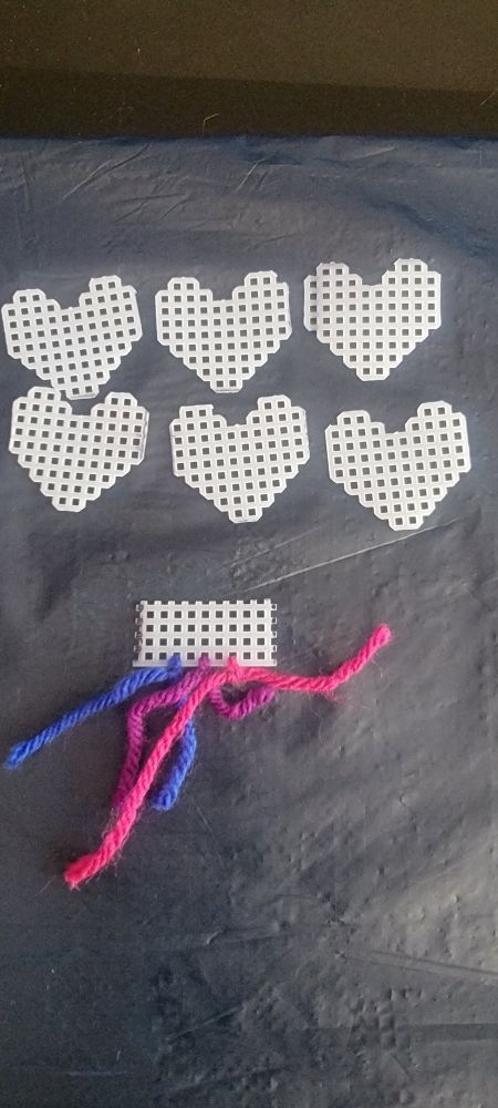 6 plastic canvas hearts with palette under with the bisexual colors.
