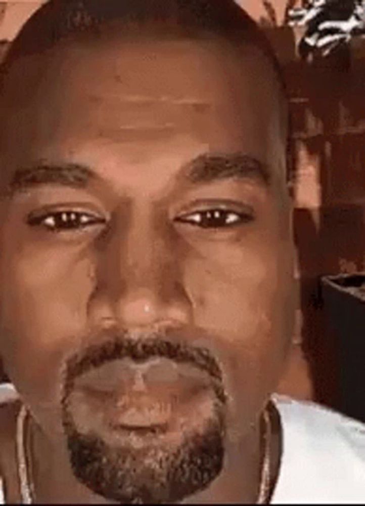 a close up of kanye west 's face with a beard and earrings .