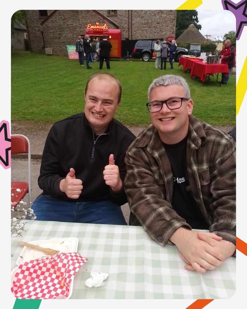 Two volunteers sat at a picnic table smiling at the camera