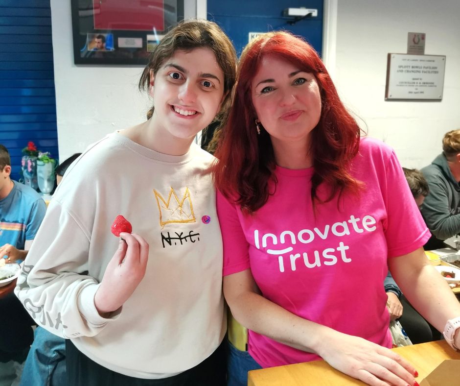 Lourdes and Lisa standing together at event - Lisa wearing pink Innovate Trust t-shirt.