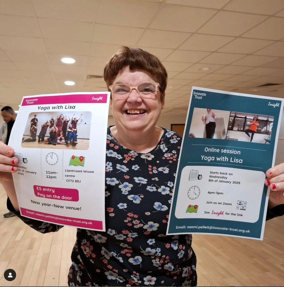 Natalie holding up 2 posters with details of upcoming yoga classes