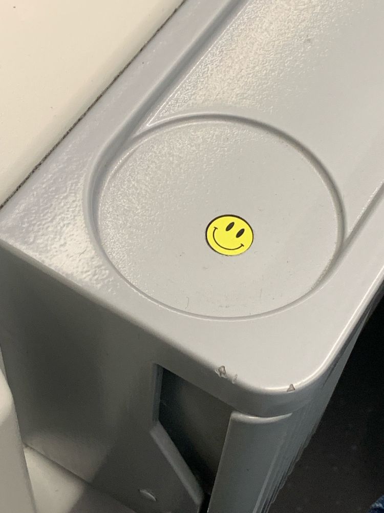 Zu sehen ist ein Aufkleber auf einem Mülleimer in einer Hamburger S-Bahn. Er zeigt einen Smiley.