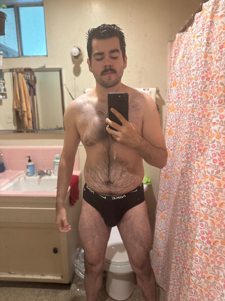 Mirror selfie in bathroom. Man is hairy and wearing black Nike briefs