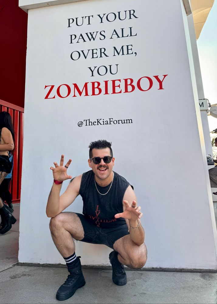 Man posing in front of Mayhem Ball sign