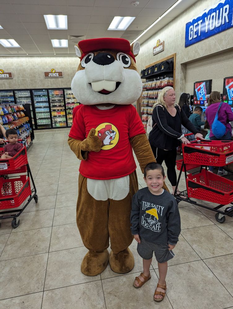 Young boy posing with a massive grin alongside Bucky the Beaver