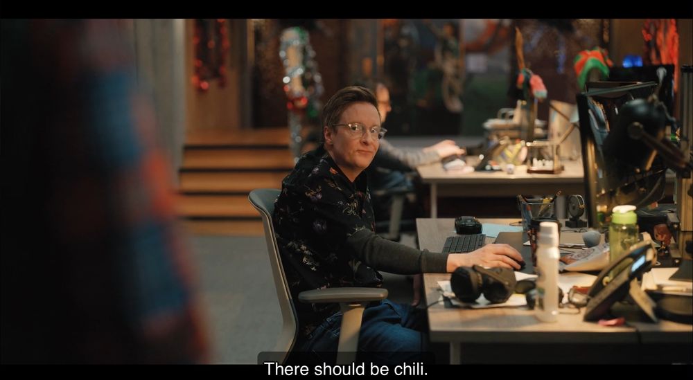 A screencap of an employee at Mythic Quest looking unimpressed after saying (close captioned) ’There should be chili.’