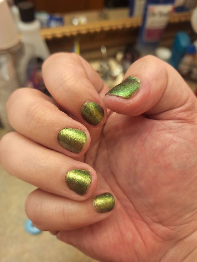 My hand with Fey & Fiend's green w/ bronze flash "I am that very witch" nail polish.