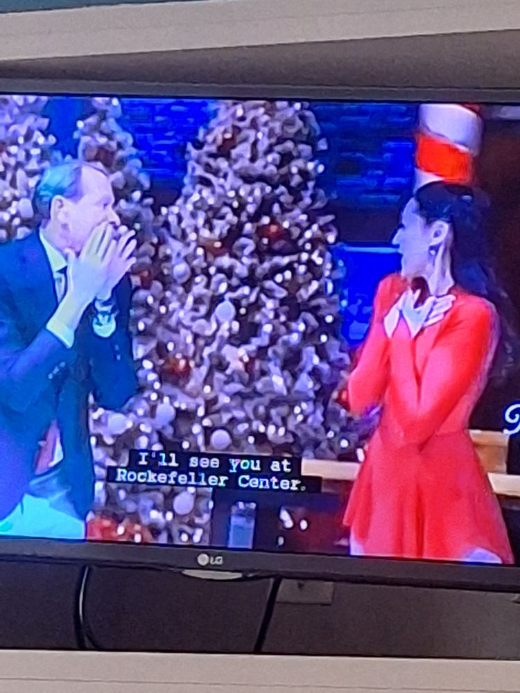 Carson Cressley stage whispering to the woman he skated with. Closed caption reads "Ill see you at Rockefeller Center"