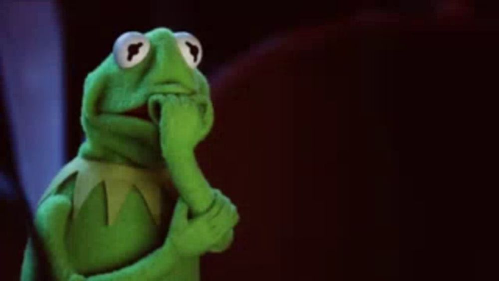 kermit the frog from the muppet show is holding his hand to his chin .