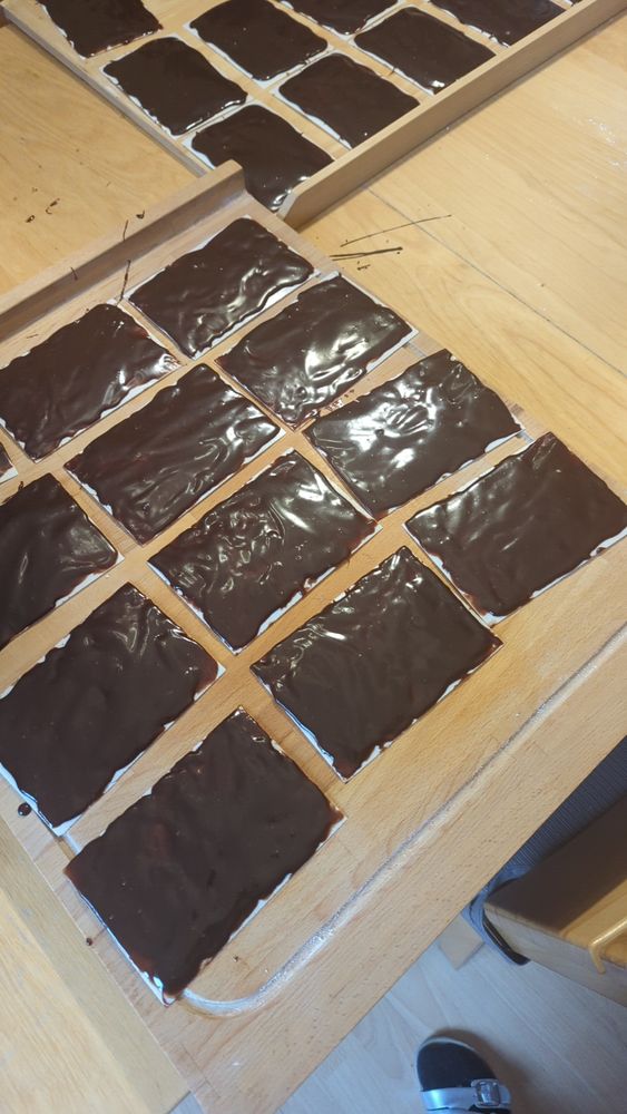 Einzelne Lagen Schokoladinchen (Oblaten mit Schokocreme bestrichen) noch nicht gestapelt auf zwei Backbrettern