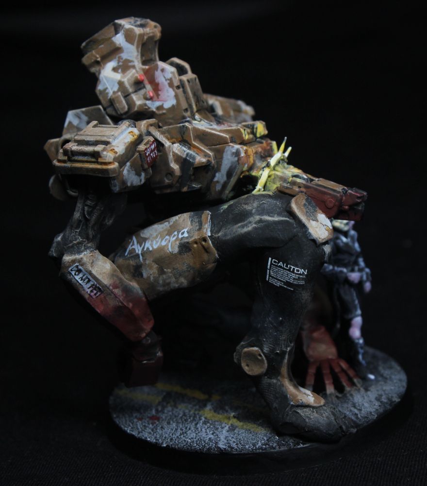 Side view.
The mech is covered with warning signs, including "do not pet".
Its personal name, Ancyor, is written on its thigh armour in Ancient Greek.
Its hands are completely covered in something that looks like blood.