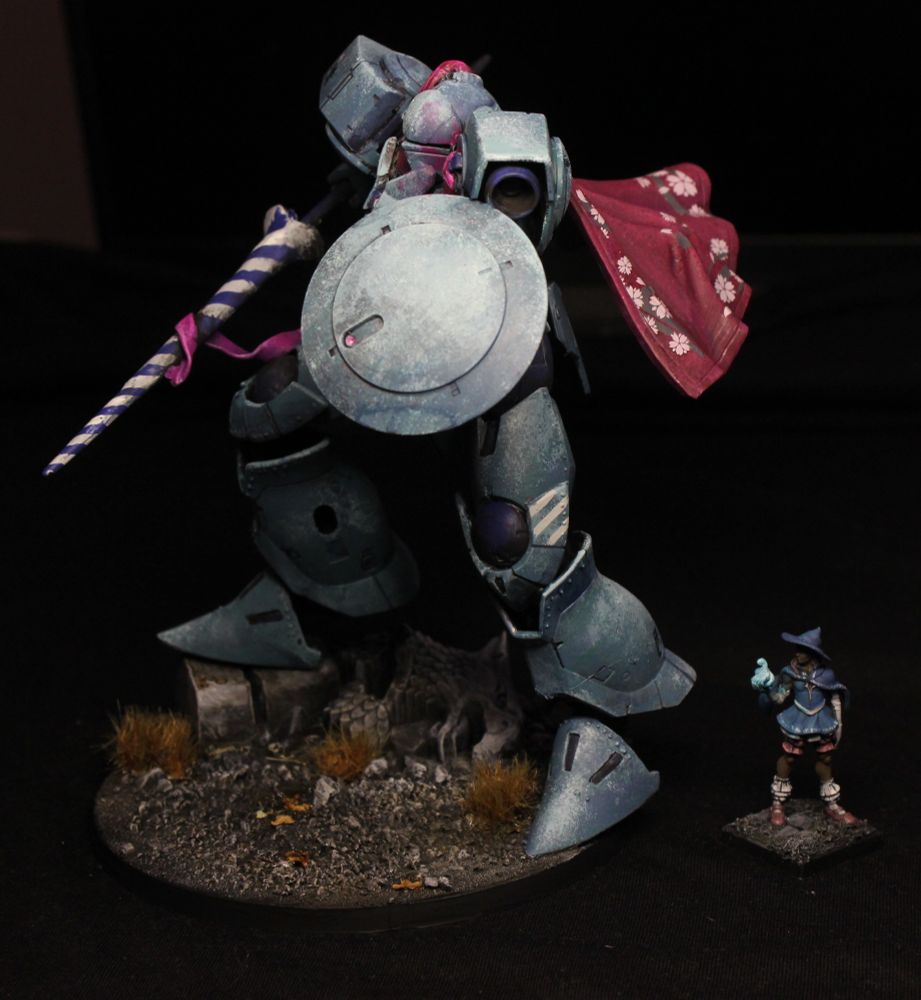 A large, teal knight standing next to a human-sized wizard.
The knight is maybe four times taller, and much wider. It is wearing a red cape with pink cherry flowers, and a jousting lance striped white and blue.