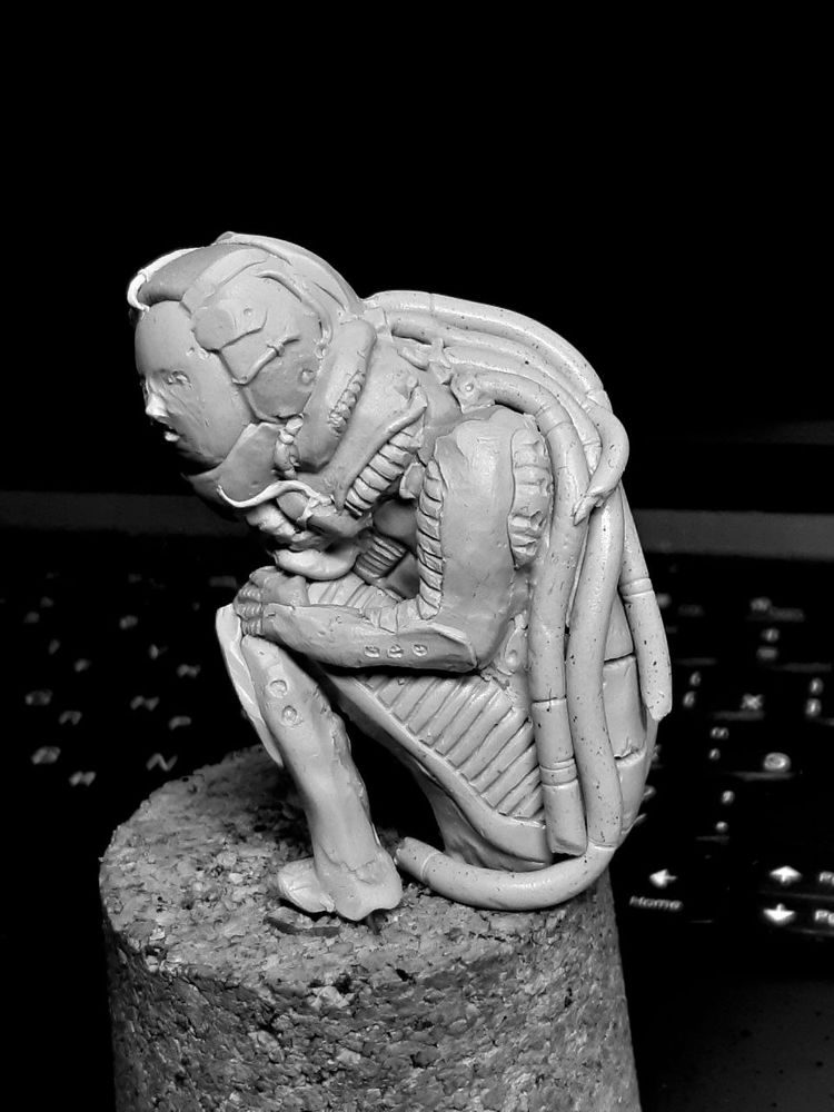 A sitting figure of an enormous biomechanical person.