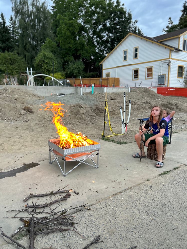 A construction site with a bonfire on it. A 12yo tending the fire.
