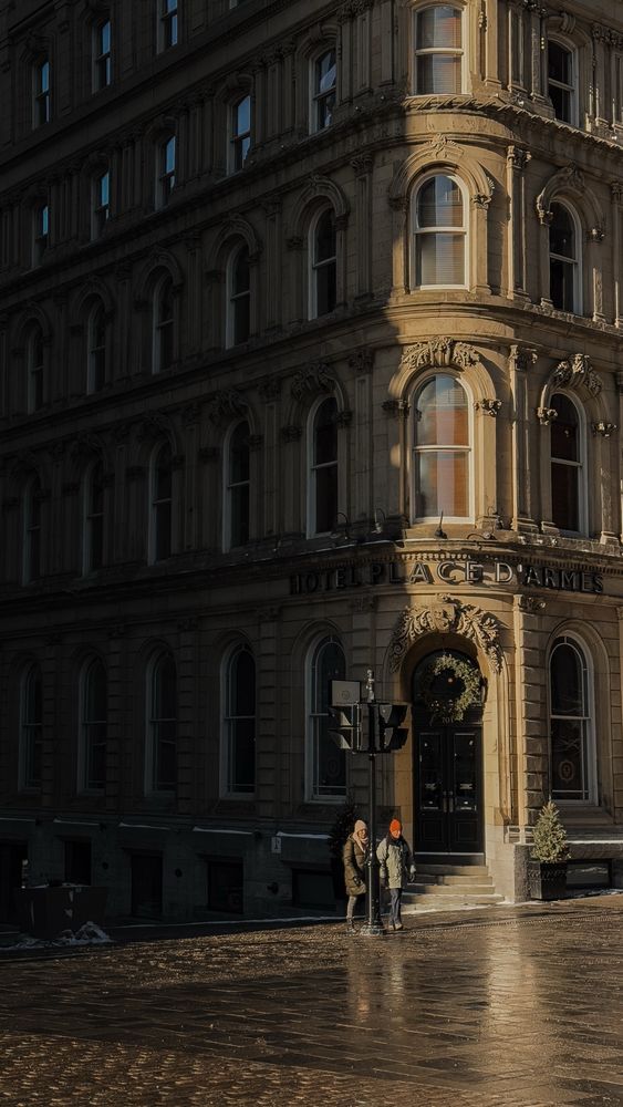 Façade d’un bâtiment à Montréal éclairé par le soleil : la partie gauche est complètement dans l’ombre et deux personnes qui traversent sont éclairées par la lumière du jour