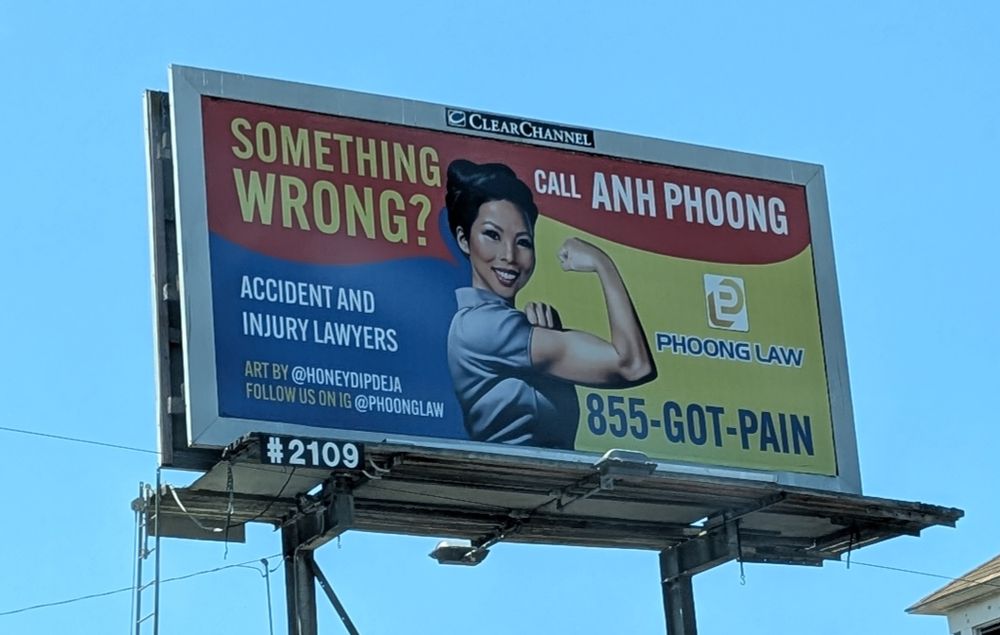 an accident lawyer billboard for anh phoong showing her in a Rosie the Riveter pose with the caption "something wrong? call anh phoong"