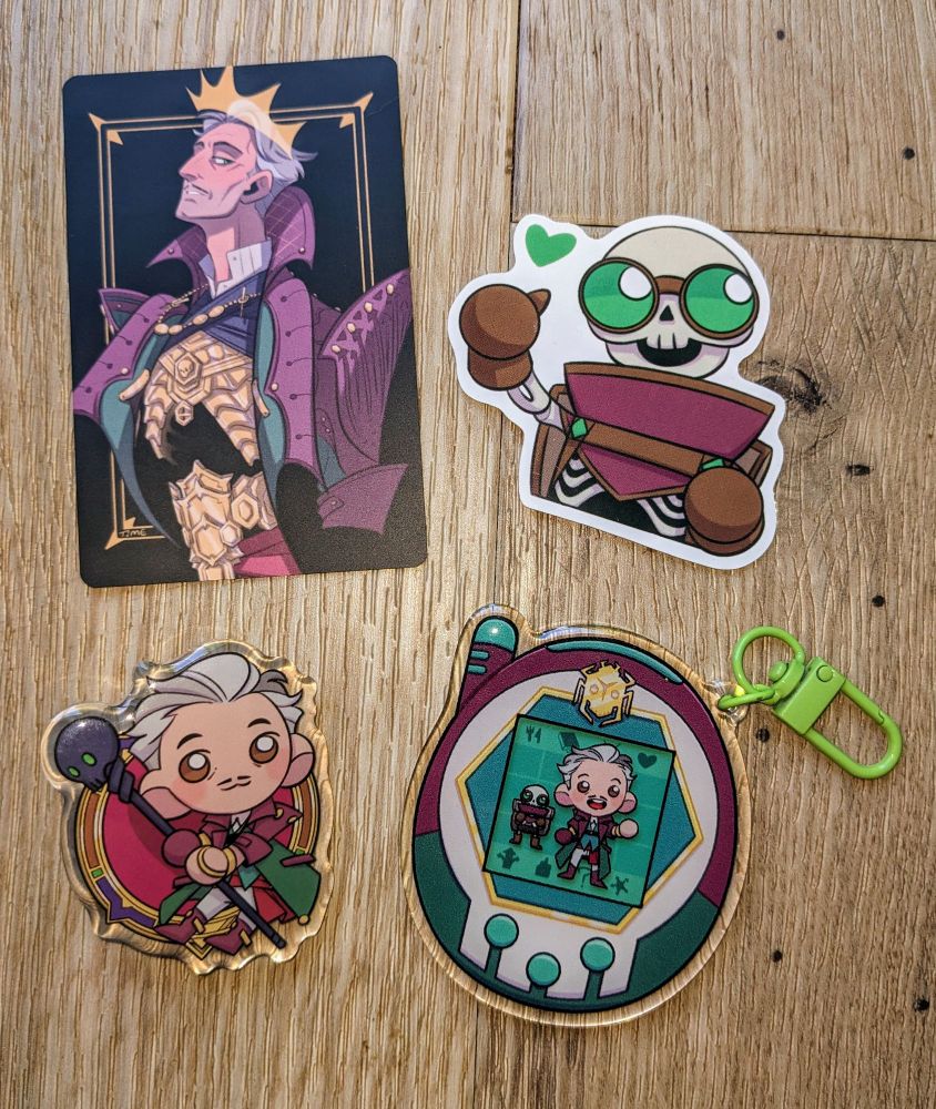 A small print, an acrylic pin and a Tamagotchi charm of Emmrich and a Manfred sticker by the wonderful TimetheHobo