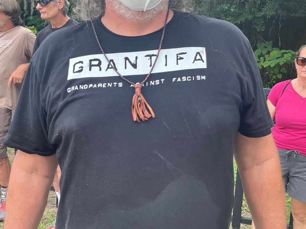 Torso of a person standing in the sun and wearing a black T-shirt reading l
“GRANTIFA: GRANDPARENTS AGAINST FASCISM”