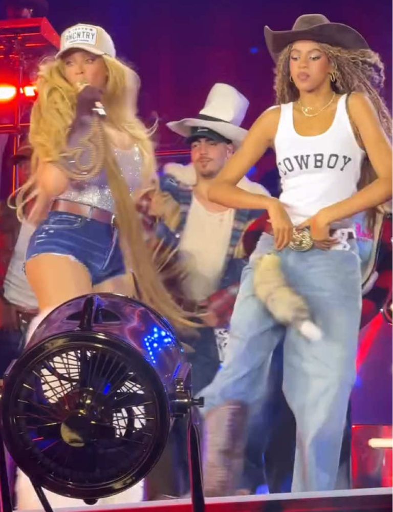 Blue Ivy Carter on stage wearing jeans, tshirt, cowboy hat aaaaaaaaaand a badger tail on her hip (?)