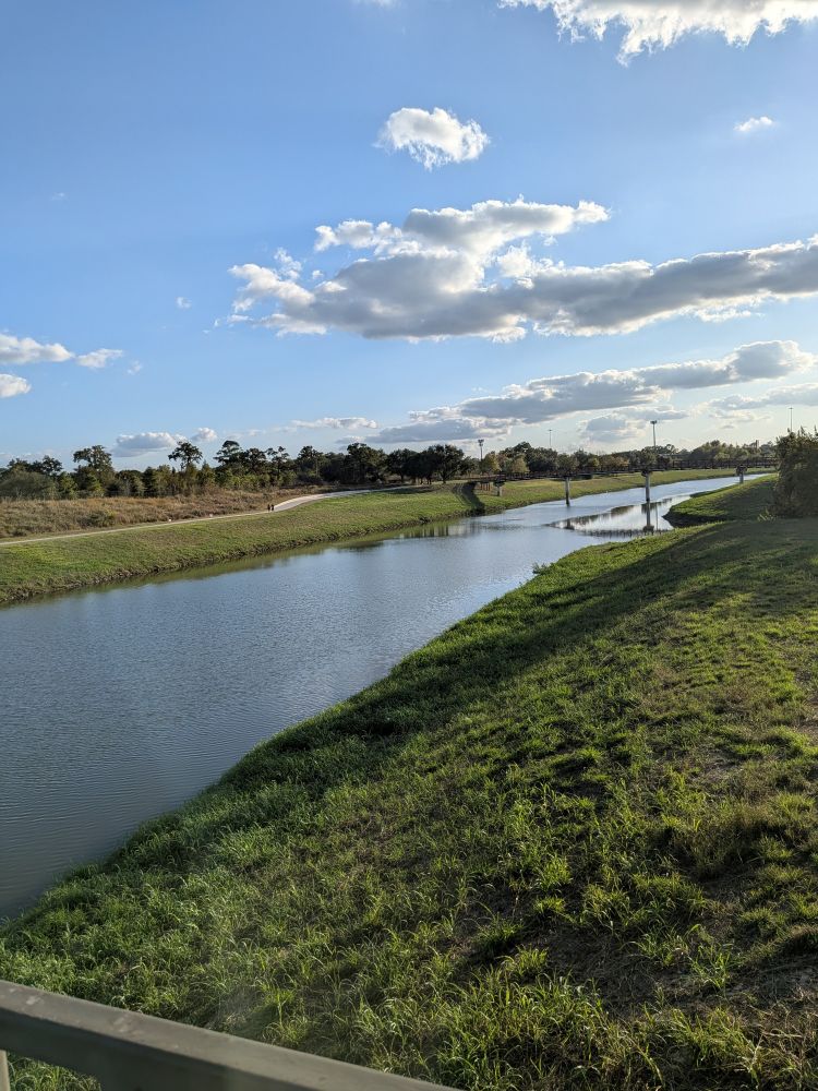 riverbank with grass on both sides and blue sky 