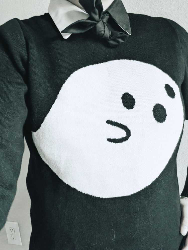 person wearing a black sweater with white ghost  over collared shirt. 
