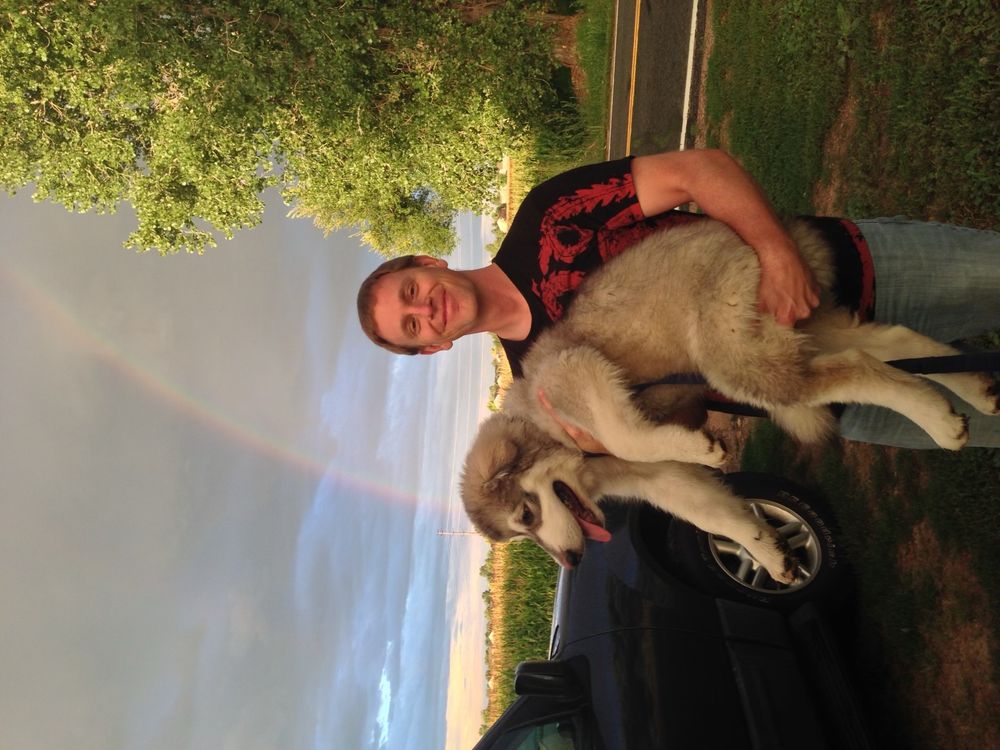 Me holding my dog, rainbow in background.