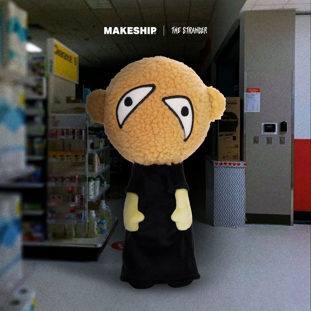 A plush toy of The Stranger, a black robed figure with an oversized textured head, haphazardly painted on (?) eyes on a featureless face