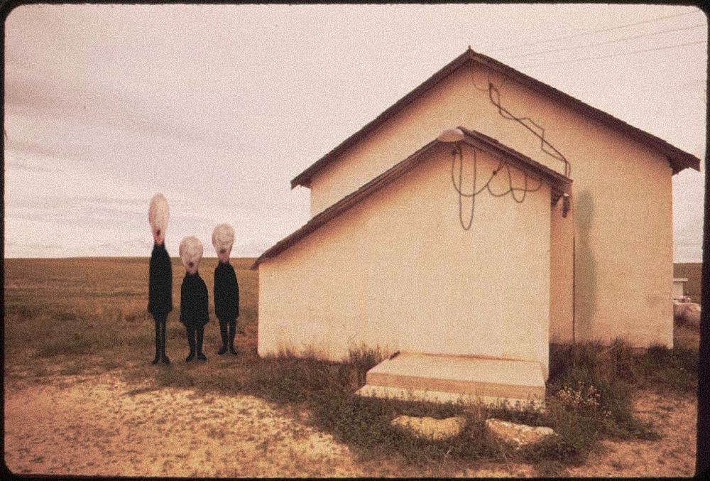 three diminutive figures with featureless faces stand beside a small house on an empty plain. the sky is grey. the house has no doors or windows, and is draped in cables. there's a shadow of a fourth figure on the right side of the house, but nothing is casting it.