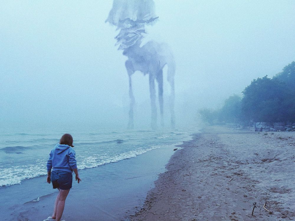 A woman stands on a misty beach. in the near distance, a giant form, something between a jellyfish, a horse and a mushroom, looms.