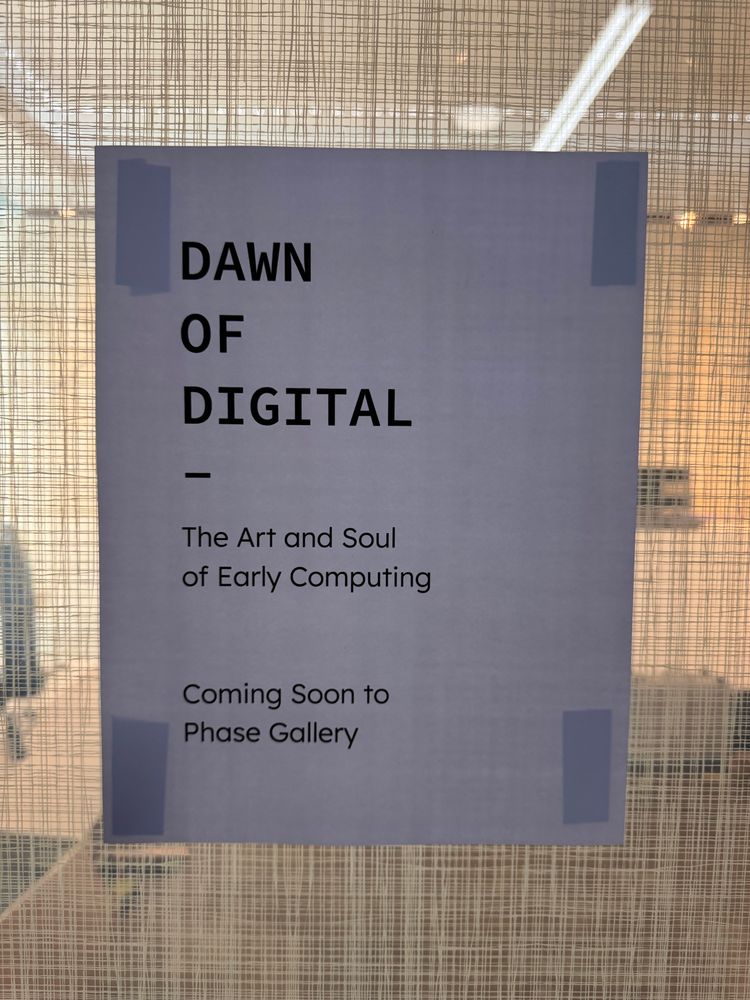 White sheet of paper, on a glass wall, announcing the Dawn of digital exhibition coming soon