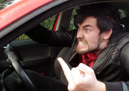 Screenshot from a driving school instructional video showing an angry car driver giving the middle finger.