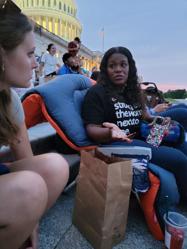 U.S. Capitol building in the background, at night, with Rep. Cori Bush sitting in to extend the eviction moratorium. 