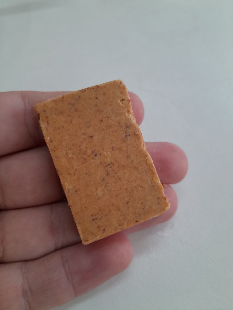 Mão segurando paçoca sobre um fundo branco.