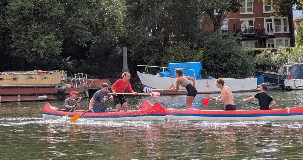 Two canoes facing off with people in the front of each trying to push the other person out