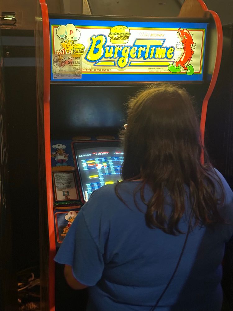 A woman playing the arcade game Burgertime. She has well over 100000 points and is going strong.