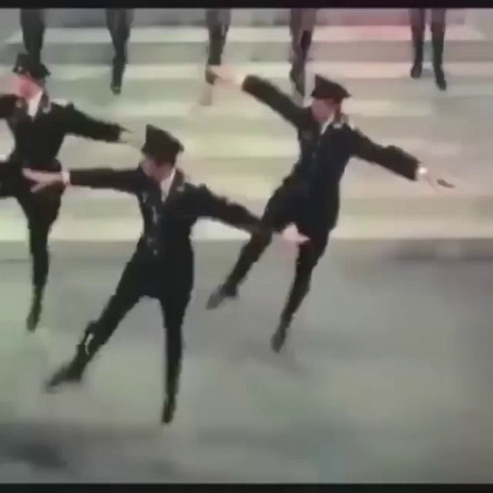 a group of men in military uniforms are dancing together on a street .