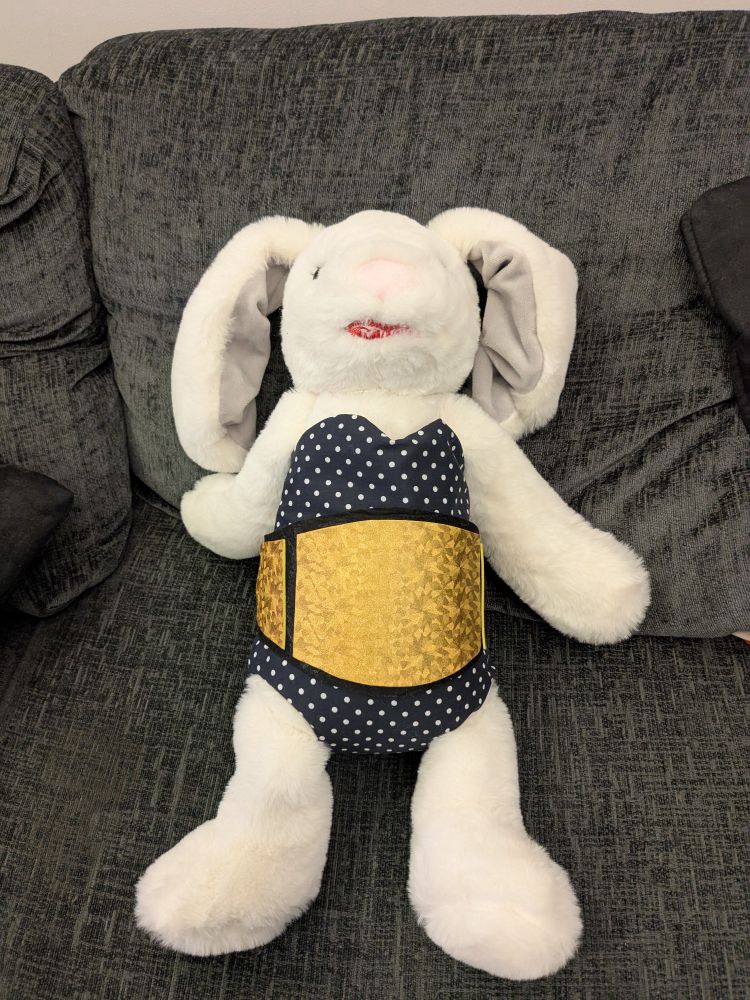 A bunny cuddly toy altered to look like wrestler Timeless Toni Storm, complete with lipstick, Georgette dotted leotard, and fabric representation of the AEW women's championship belt.