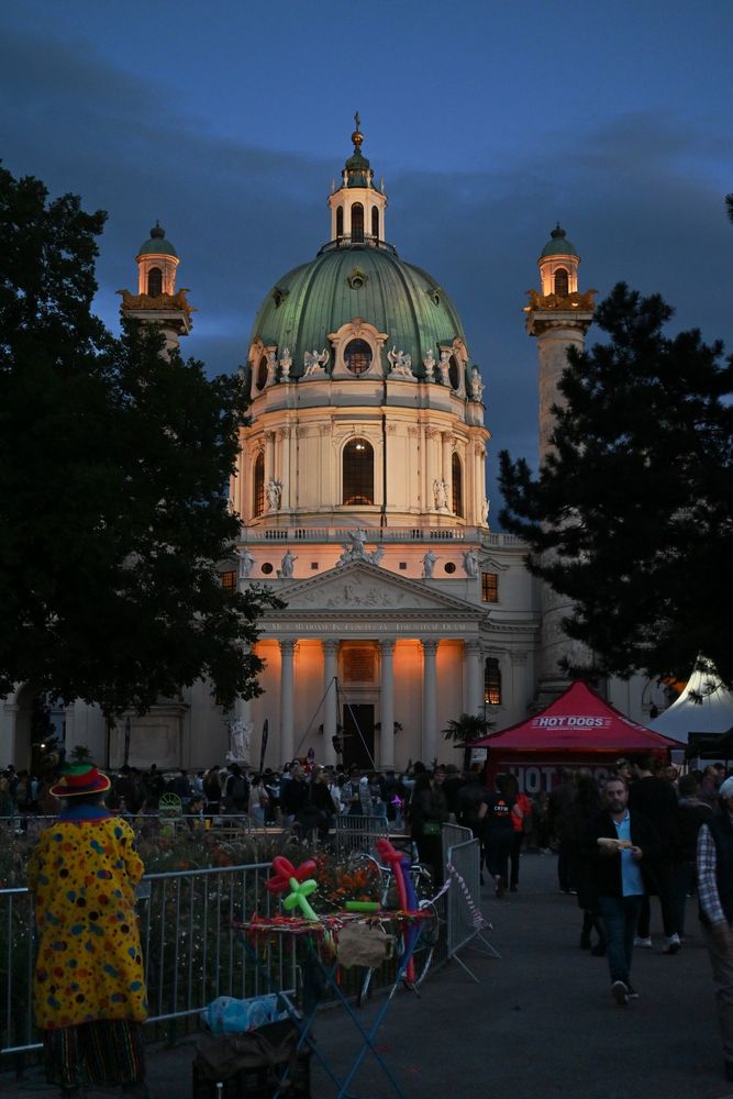 A clown looks at the Karlskirche in the dusk, at the end of the Buskers Festival in the Karlsplatz, Vienna.