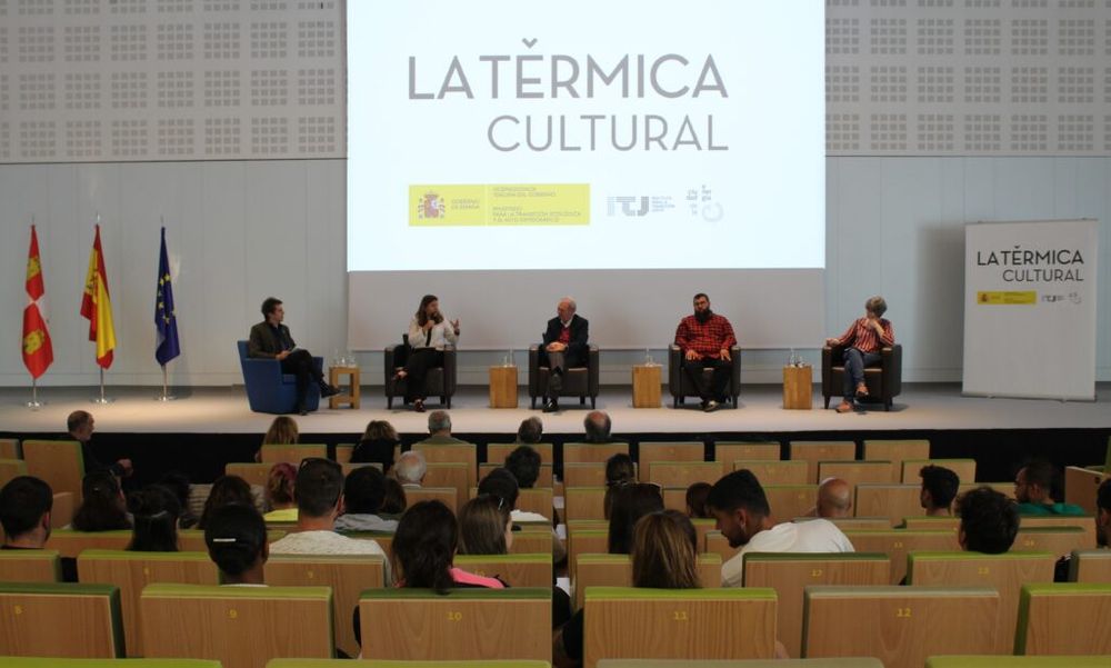 Imagen de un momento del evento. Se ve un aparte del auditorio y desde el punto de vista del público asistente. 
Sobre el escenario, de izquierda a derech y sentados en butacas: Miguel Ángel Blanco, presentador; Yasodhara López, José Ignacio Largaros, Jaime San José y Ester Pérez.
Al fondo una pantalla en la que se lee "La Térmica Cultural"