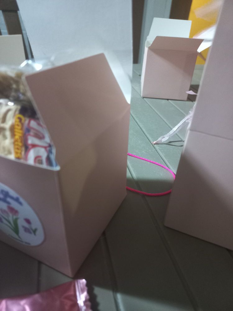 A small pink bakery box with snacks and party favors