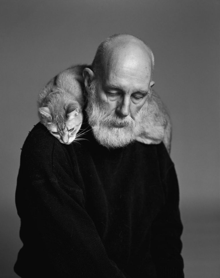 Edward Gorey wearing a black sweater, looking down, with a cat draped over his shoulders. Image by Richard Avedon. 
