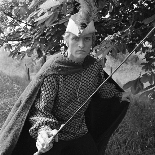 B&w photo of Rutger Hauer as Floris: a man in a shawl, with a feathered cap, brandishing a lance, standing by a tree