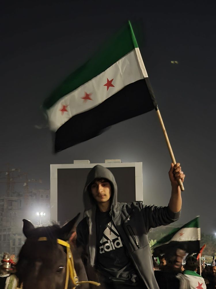 A young guy riding a horse and holding Syrian revolution flag 