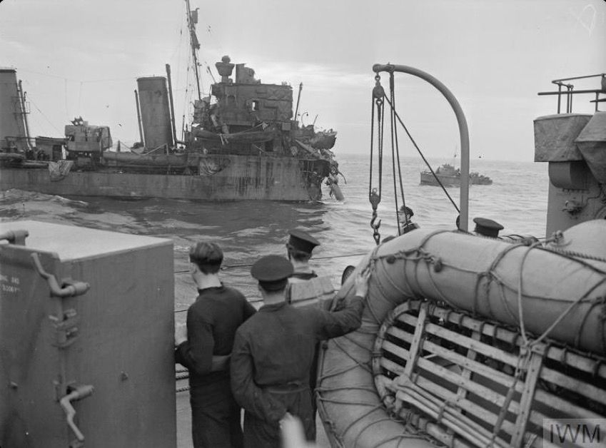 HMS Express viewed from HMS Kelvin, with the extent of her damage evident. Note the MTB standing by in the background. 📷 IWM (A 533) (Viewed from another vessel, ratings stare at a destroyer which is missing her entire bow forward of the bridge. The sea is calm and a small boat is visible in the background)