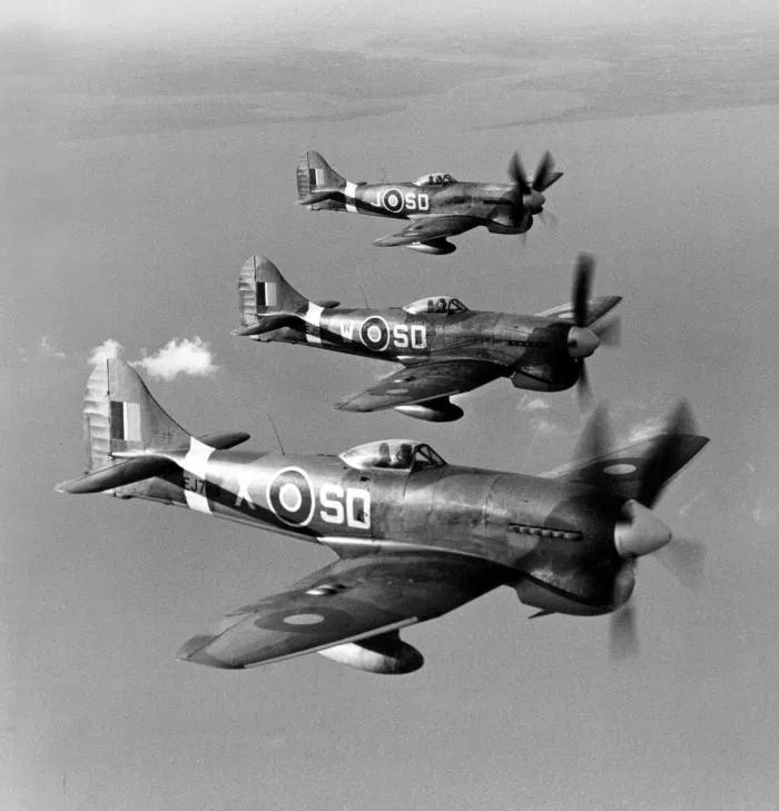 No 501 Squadron put up this trio of Tempest Vs in October 1944. Nearest the camera is EJ763/SD-X, accompanied by EJ599/SD-W (which scored four V1 kills, the final one being the squadron’s last ever) and six-kill example EJ589/SD-J. 📷 key.aero (Three Tempests in echelon left formation at altitude in clear skies. Visible behind is a river estuary)
