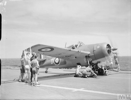 Grumman Martlet of 888 Squadron NAS warming up on board HMS Formidable prior to takeoff. 📷 IWM (A 11640) (Martlet on a carrier deck under a harsh sun, engine running. Multiple bare-chested crewmen are holding the wingtips and undercarriage)