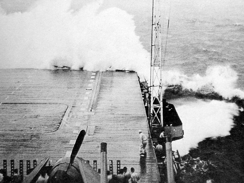 The bow of USS Hornet is hit by a wave which mangled the first 24 feet of her flight deck.
📷 National Archives

(Heavy seas crashing over the flight deck of a carrier during a storm, with crewmen looking on at a safe distance)