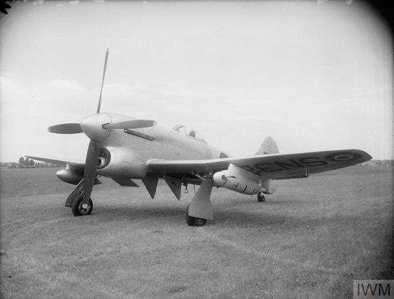 Hawker Tempest TT Mk.5, carrying a target winch pod under the port wing. These aircraft replaced the much slower types previously used as target tugs, such as the Miles Magister. 📷 IWM (ATP 16813B) (Unpainted Tempest with postwar RAF markings, carrying a drop tank under the right wing and a large cylindrical pod with a small propeller under the left wing)